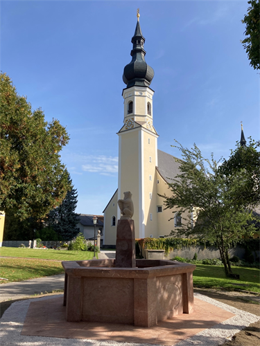 Renovierter Bärenbrunnen im Hintergrund die Pfarrkirche Berndorf